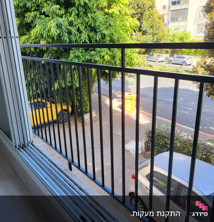 מעקה ברזל שחור במרפסת עם חלונות זכוכית פתוחים